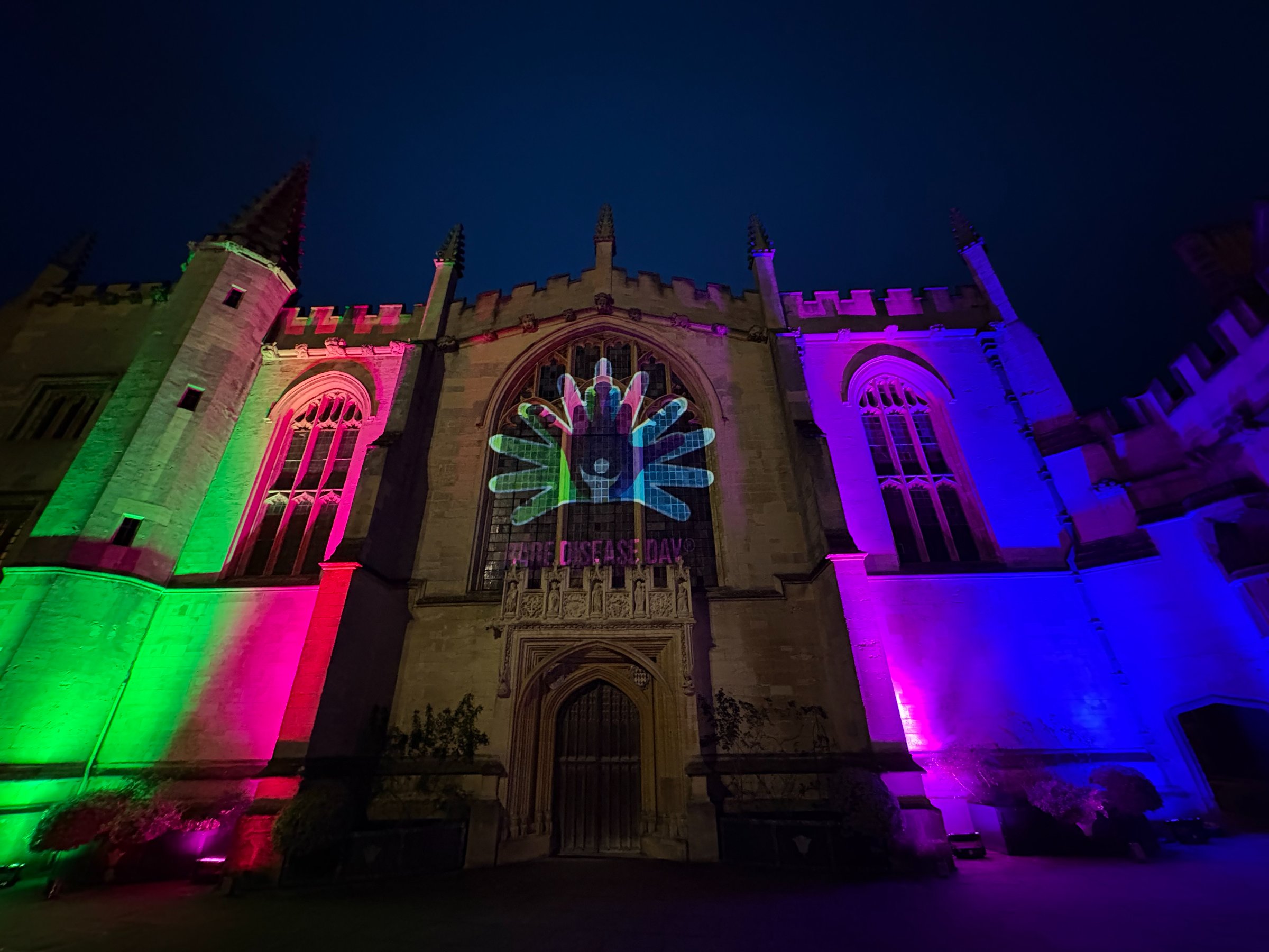 Magdalen College Oxford illuminated in pink, green, blue and purple
