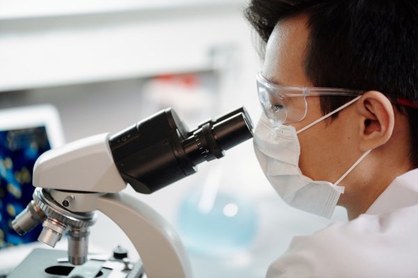 A scientist looking at a microscope in a lab setting